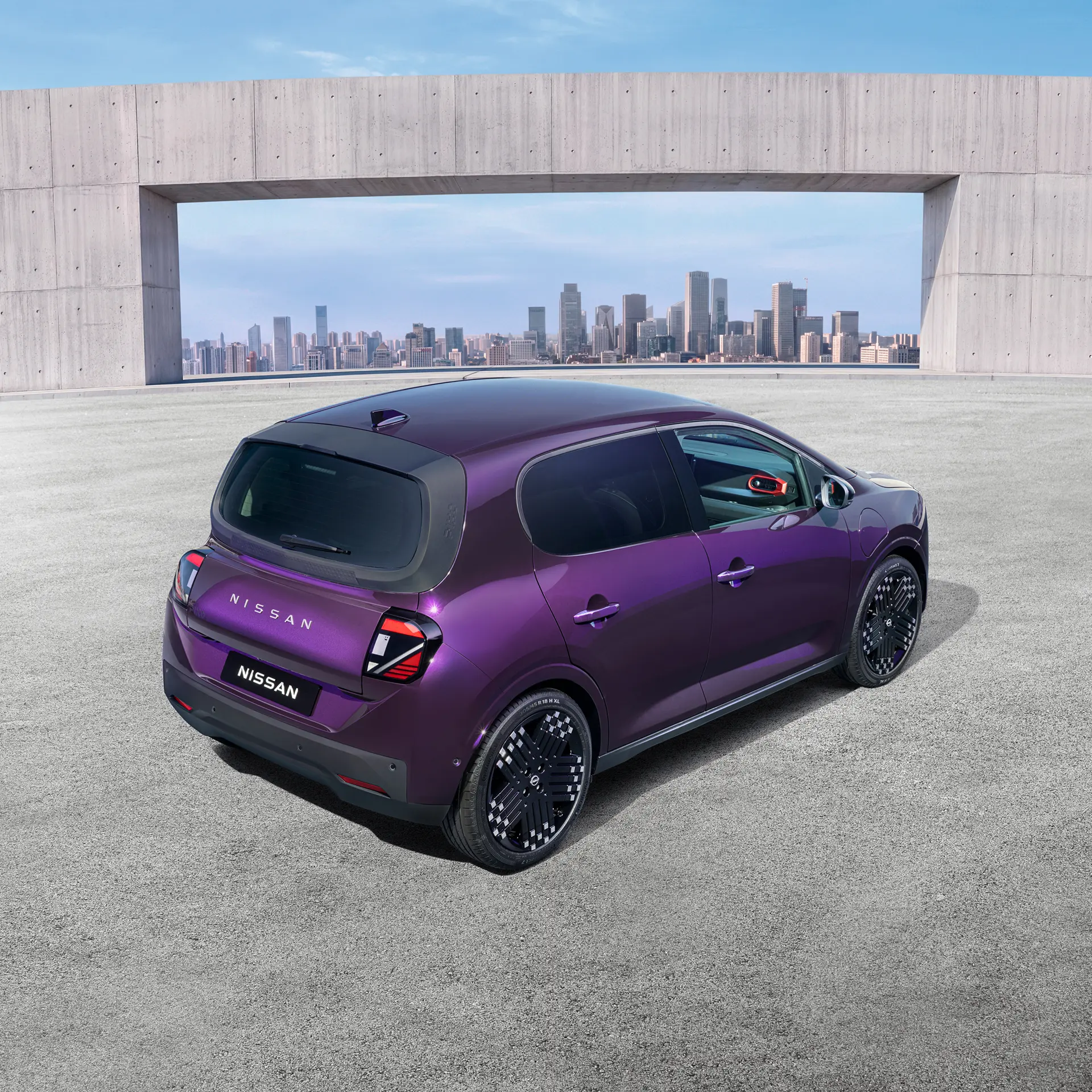 Lila Nissan PIXO hátulról, felülnézetből, betonépület és városi látkép előtt